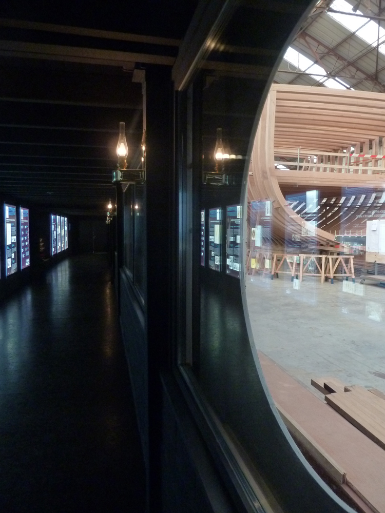 Salle d'exposition en noir avec fénêtre ronde
