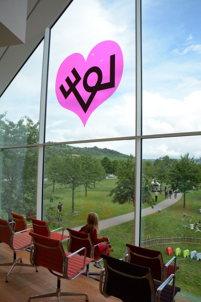 Showroom VITRA in VITRAHAUS, view on surrounding nature, Eames chairs, pink heart sticker on glass